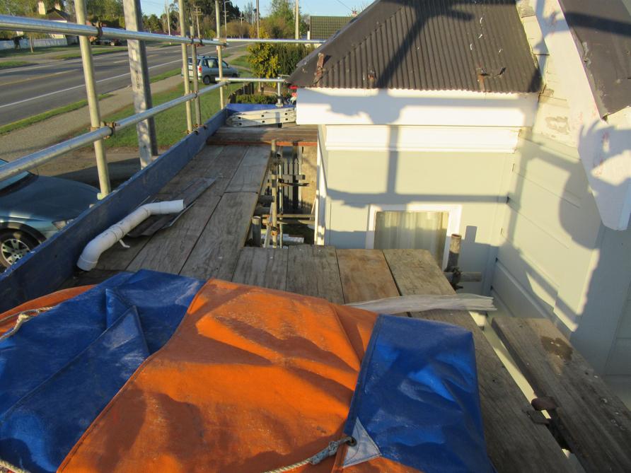 4 Ronaldsay St Palmerston Up on the scaffolding at the front of the house looking at the old roofing and what needs to be done