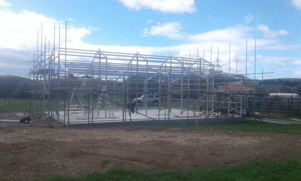10 Heritage barn Dunback Side on view of the almost completed steel frame work having been erected for the barn with scaffolding in the foreground JDBuilders