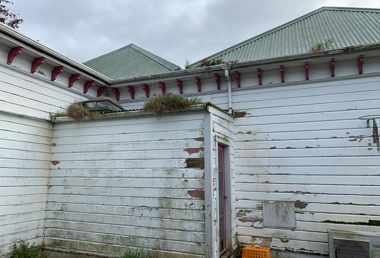 B8 9 Fifield St, Roslyn, Dunedin Back of the house with grass growing from the spouting, patched hole and rotten weatherboards, before renovation JDBuilders LR