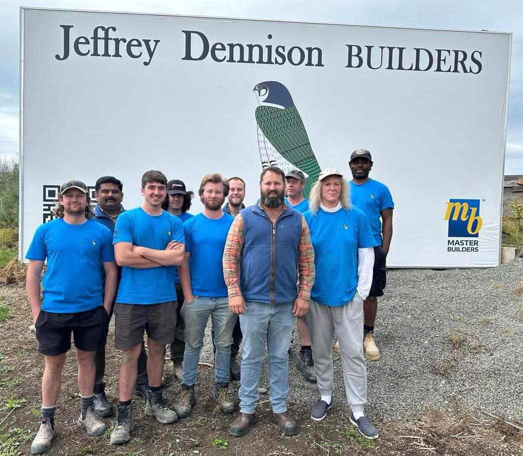 The staff of JDBuilders in front of their large sign 5 minutes south of Omaru on State Highway One