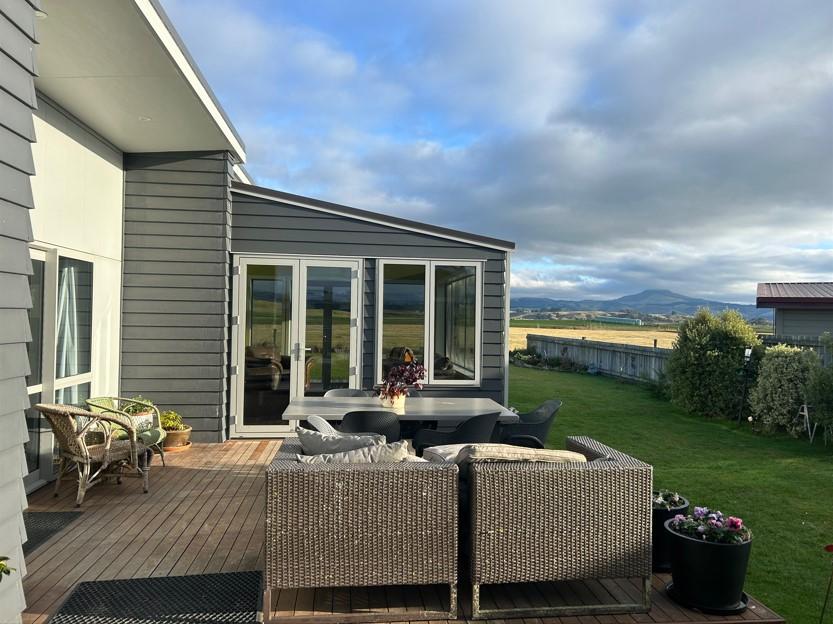 Main Construction of a new conservatory in Karitane, with several outdoors chairs in the foreground on the decking JDBuilders